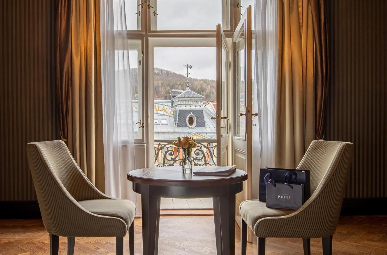 Grandhotel Pupp Karlovy Vary Luaran gambar The photo depicts a cozy interior setting, likely within a hotel room or a private space. There are two elegant chairs positioned around a round wooden table. On the table, there is a small vase with flowers, adding a touch of warmth to the environme