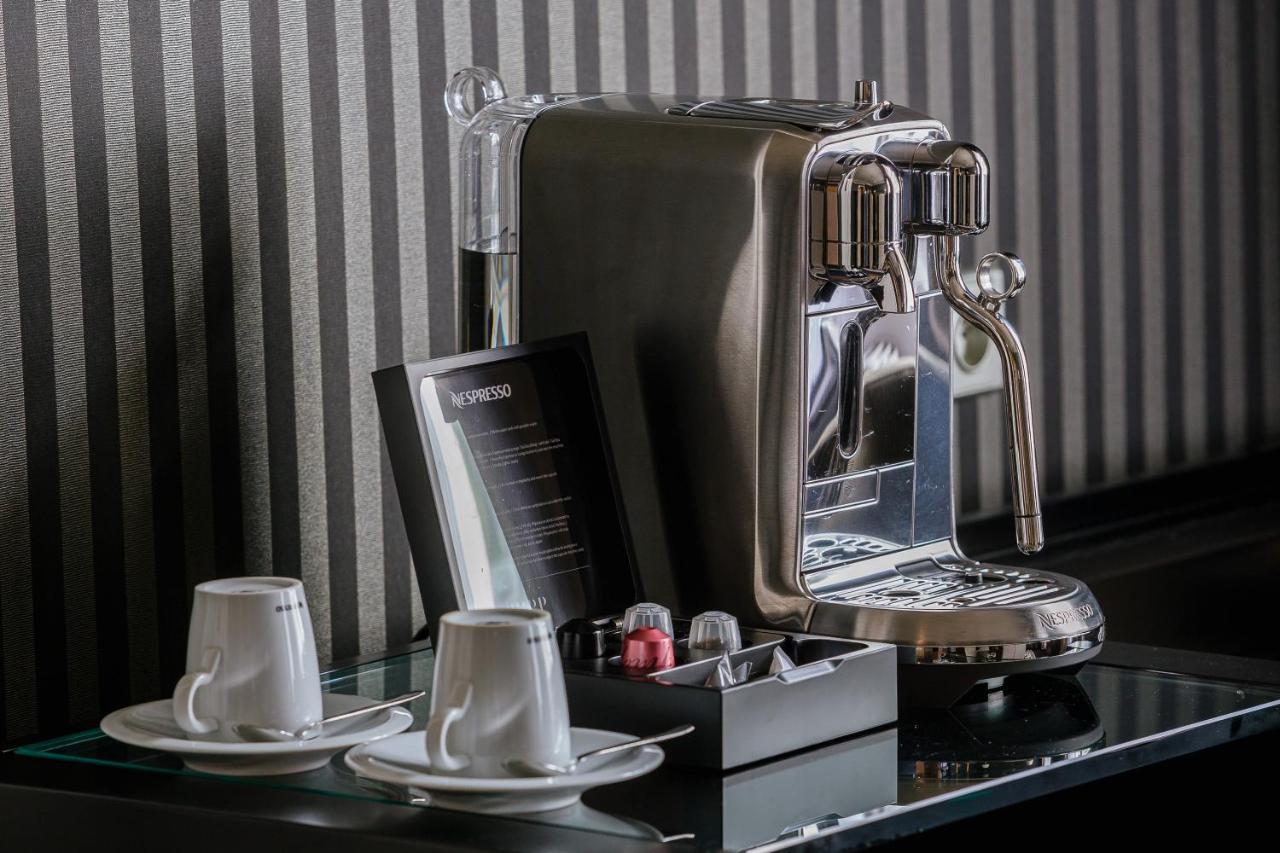 Grandhotel Pupp Karlovy Vary Luaran gambar The photo shows a sleek, modern coffee machine positioned on a countertop. The machine has a shiny, metallic finish and is equipped with a faucet for dispensing coffee. Next to the coffee machine, there are two white coffee cups on small saucers. In 