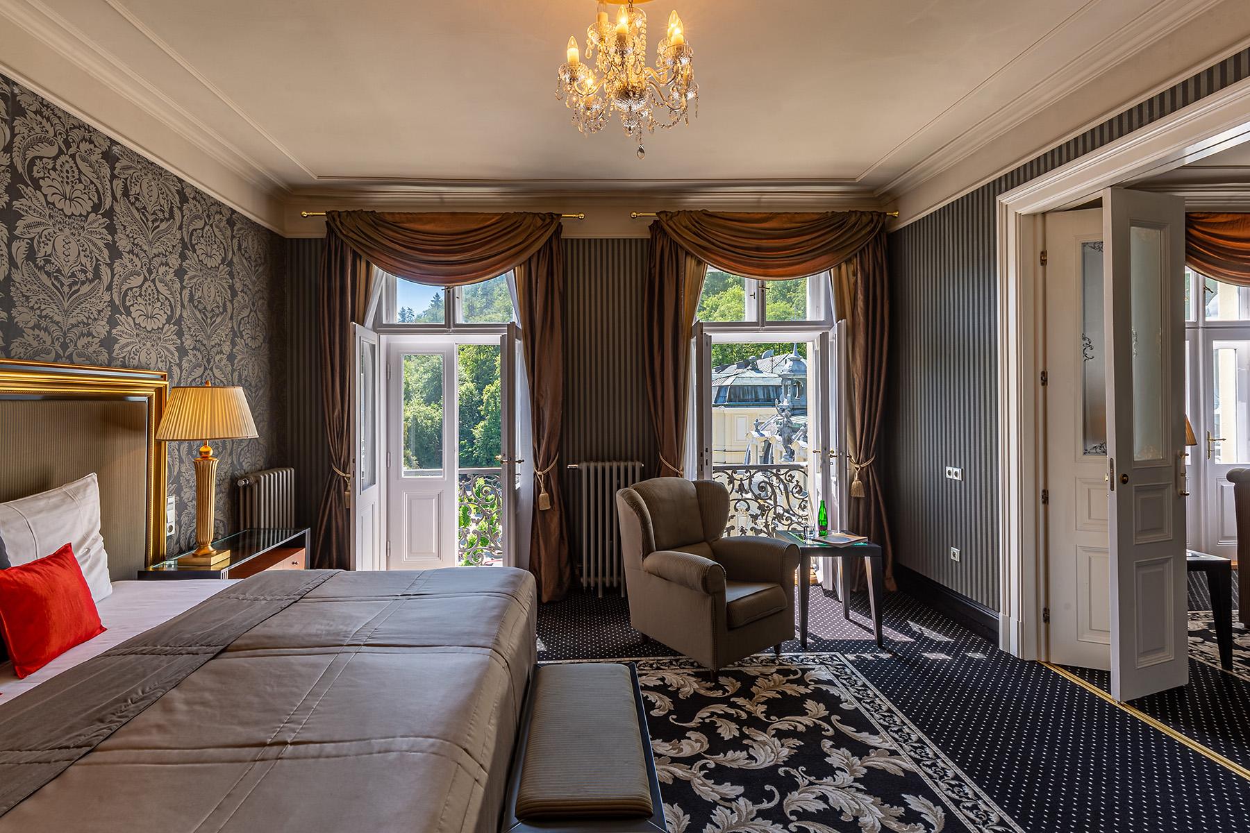 Grandhotel Pupp Karlovy Vary Luaran gambar The photo shows a beautifully decorated hotel room or suite. It features a large bed with a stylish headboard and luxurious bedding. The walls are adorned with elegant wallpaper, and there are draped curtains framing two large windows that let in nat