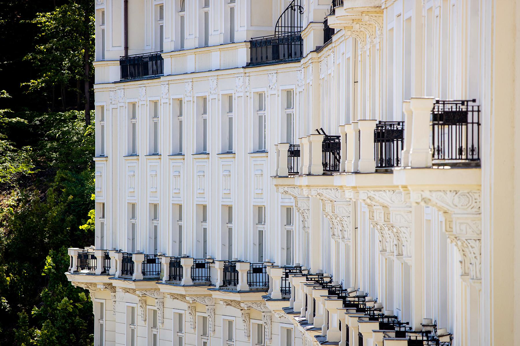 Grandhotel Pupp Karlovy Vary Luaran gambar The photo shows a section of a building facade with multiple floors. The exterior is predominantly white, featuring a series of rectangular windows arranged symmetrically. Each floor has several balconies with black railings, providing an elegant tou
