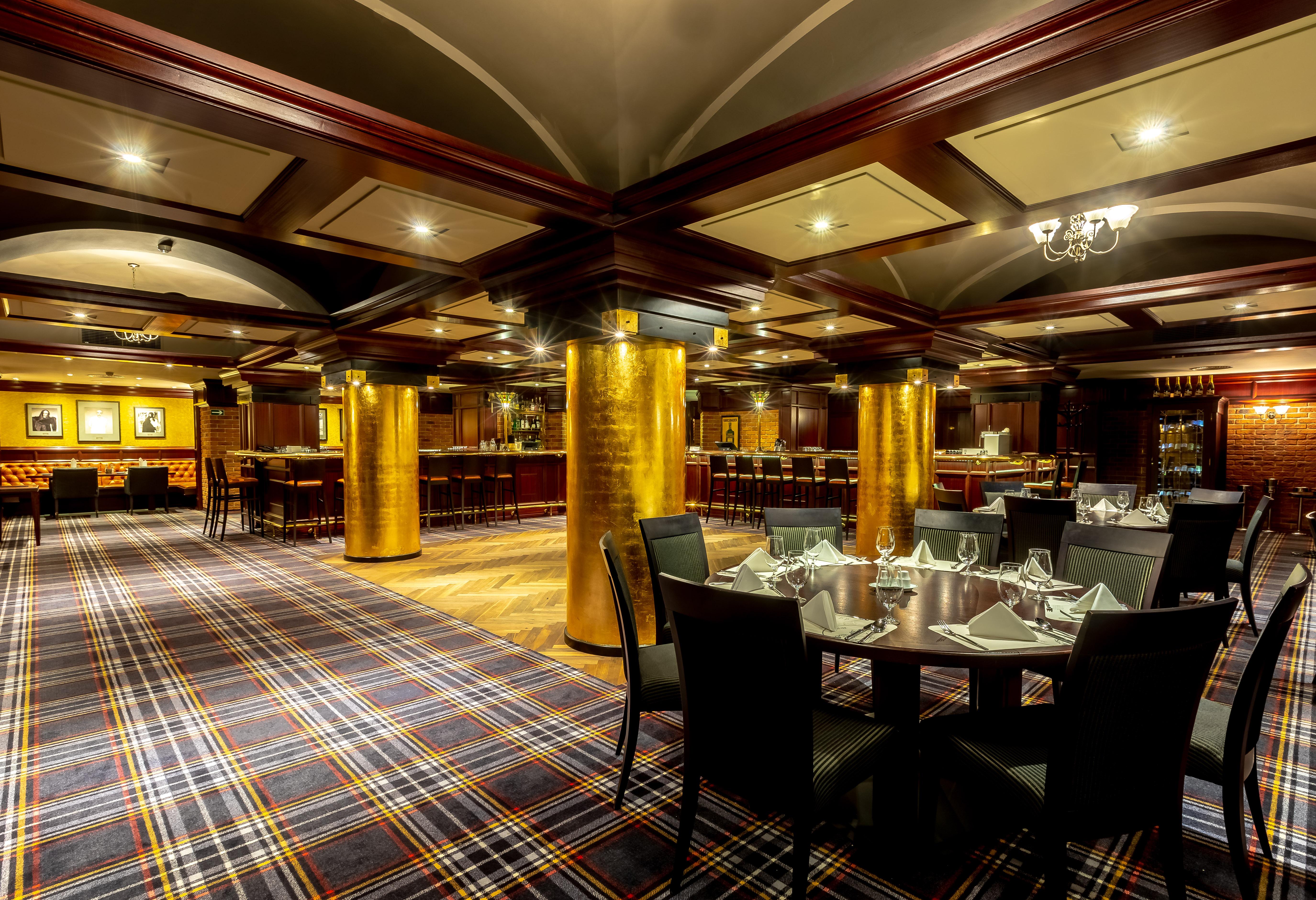 Grandhotel Pupp Karlovy Vary Luaran gambar The photo shows an elegant dining area in a restaurant. The interior features a modern design with a checkered carpet and wooden accents. Golden columns are prominent in the space, adding a touch of luxury. The tables are set with neat tableware, and