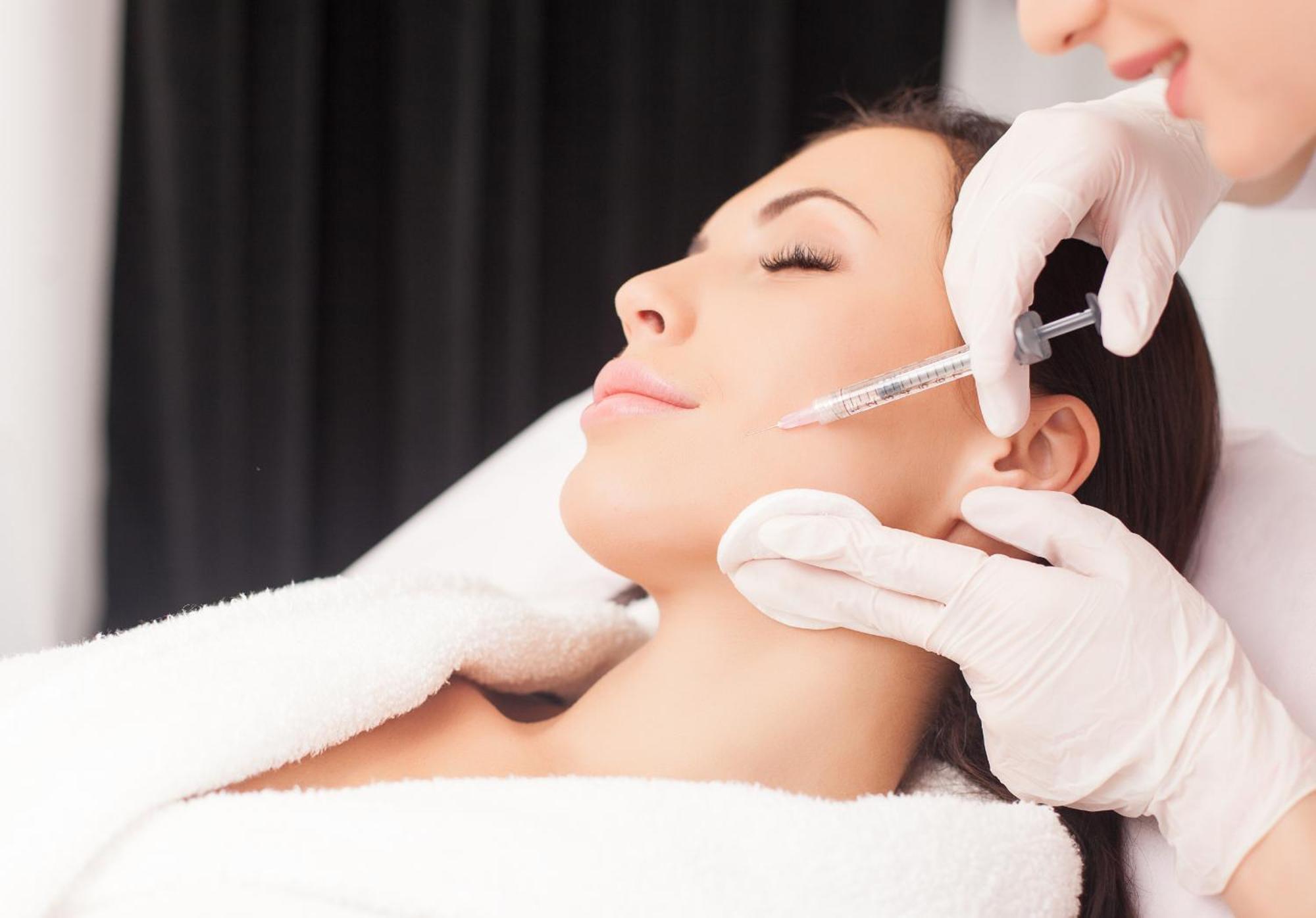Grandhotel Pupp Karlovy Vary Luaran gambar The photo depicts a woman receiving a cosmetic treatment in a spa or clinical setting. She is reclining with her eyes closed, appearing relaxed. A professional, wearing gloves, is administering an injection to her face, likely as part of a procedure 