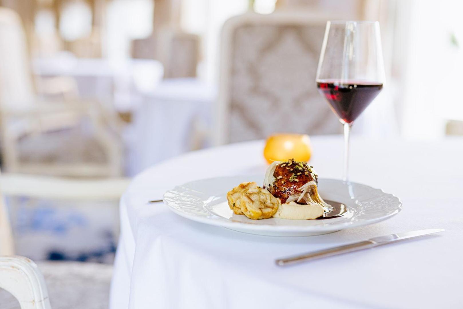 Grandhotel Pupp Karlovy Vary Luaran gambar The photo shows a beautifully arranged dining table setting. On the table, there is a white plate containing two food items: one appears to be a meatball or similar dish, and the other looks like a golden-brown pastry or fritter. Accompanying the dis
