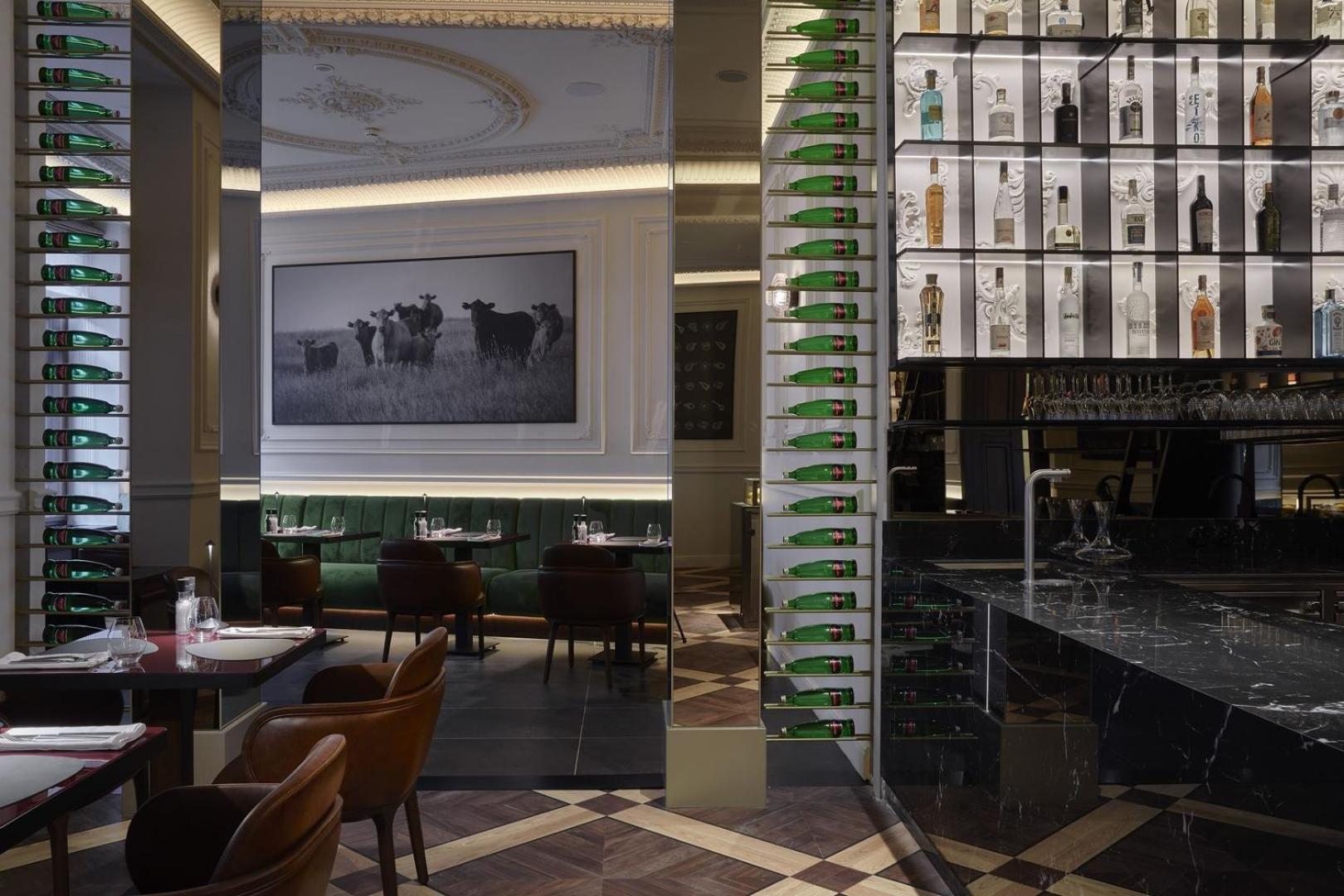 Grandhotel Pupp Karlovy Vary Luaran gambar The photo shows the interior of a stylish restaurant. There is a large photograph of cows on the wall, adding a rustic touch to the decor. The space features elegant seating with dark brown chairs, and the tables are set for dining. A bar area is vis