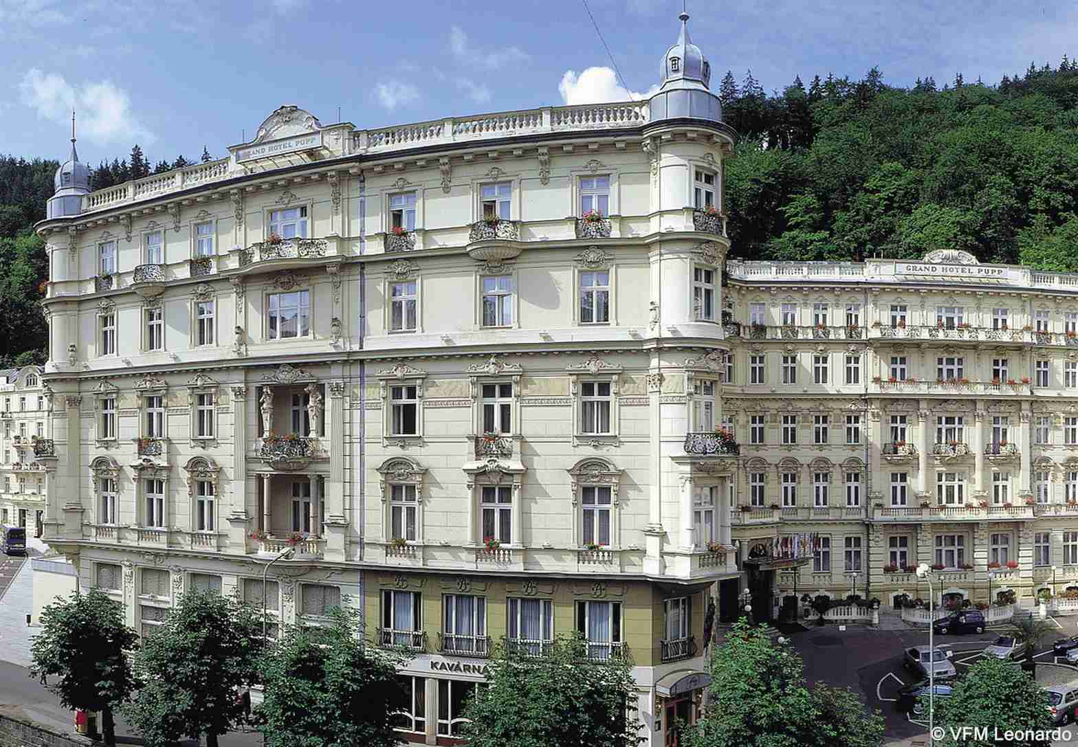 Grandhotel Pupp Karlovy Vary Luaran gambar The photo shows a beautiful architectural scene featuring two elegant buildings. The structures exhibit a classic design with intricate details, large windows, and ornate balconies. They are painted in a light color, possibly cream or pale yellow, wh
